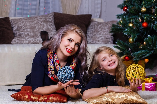 Happy mother and daughter posing against the Christmas tree Christmas and new year mood closeup