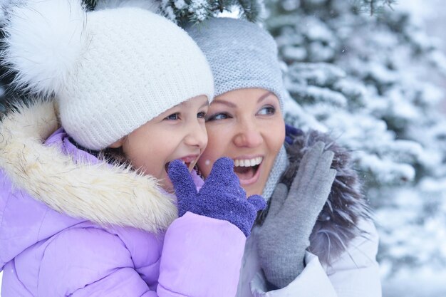 Happy mother and daughter, posing outdoors in winter