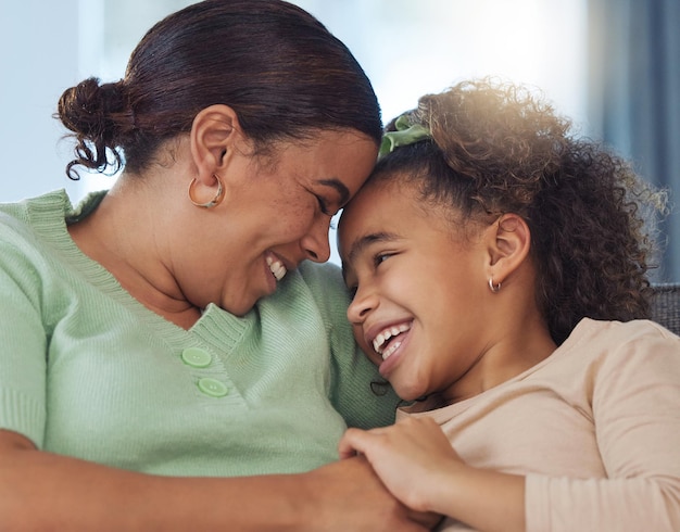 happy mother daughter and relax with hug for love care or embrace on sofa together at home mom child or kid with smile for bonding holiday or weekend in comfort safety or protection at house