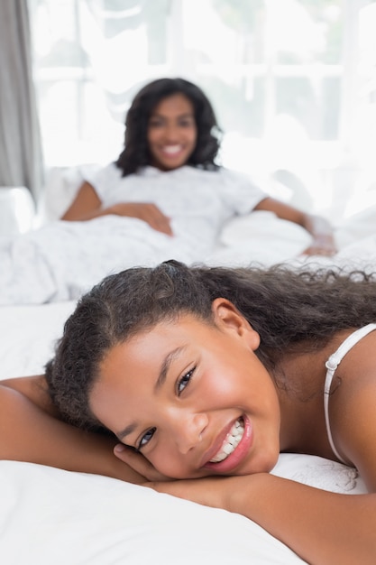 Happy mother and daughter relaxing on bed together