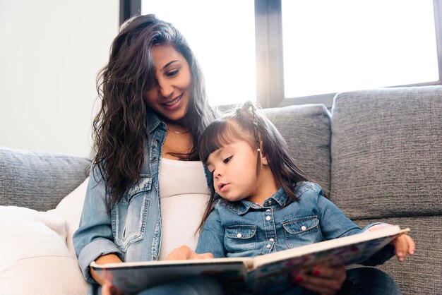 Photo happy mother and daughter sitting on sofa at home