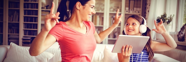 Foto madre e figlia felici che usano la tavoletta digitale e ballano