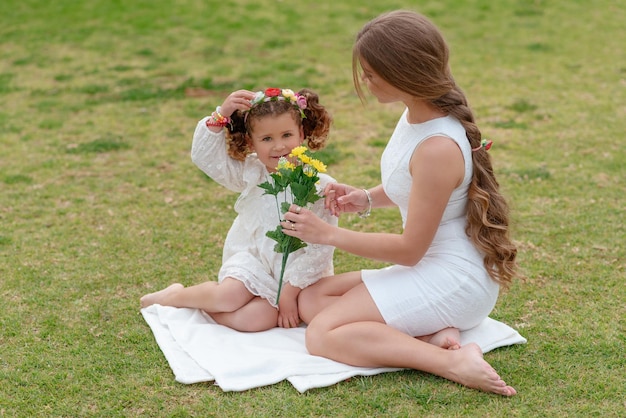 屋外の公園で黄色い花を持つ幸せな母と娘