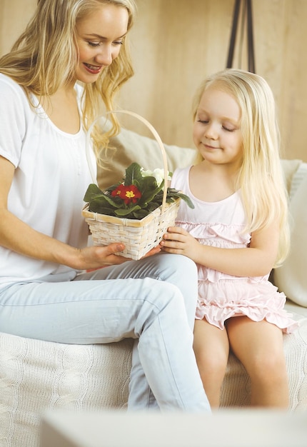 Happy mother day. Child daughter congratulates mom and gives her basket of spring flowers. Family and childhood concepts.