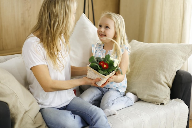 Happy mother day Child daughter congratulates mom and gives her basket of spring flowers and postcard with heart drawing Family and childhood concepts