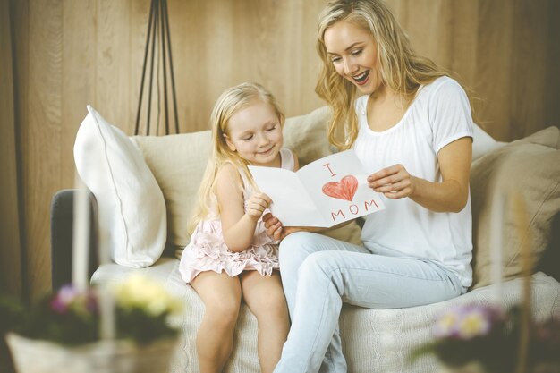 Happy mother day. Child daughter congratulates mom and gives her postcard with heart drawing. Family and childhood concepts.