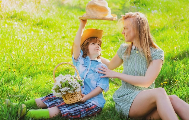 公園の芝生の上に座っている子供とピクニック家族のお母さんで息子と幸せな母の日