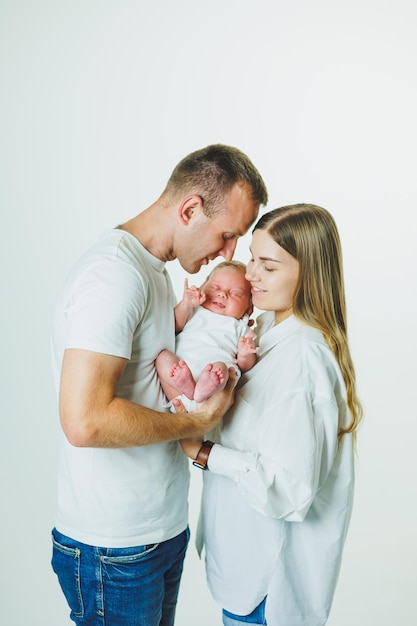 Счастливые мать и отец обнимают своего новорожденного ребенка Родители с улыбающимся ребенком на руках Молодая семья с новорожденным ребенком