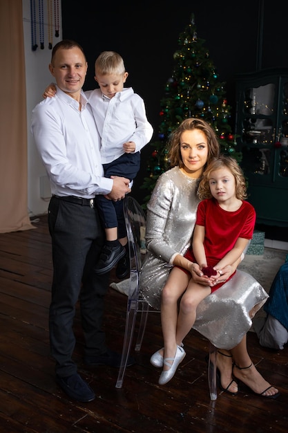 Felice madre padre e bambini piccoli vicino all'albero di natale godendo del tempo insieme durante le vacanze buon natale e felice anno nuovo