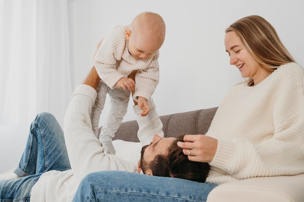 Photo happy mother and father spending time with their baby on the sofa