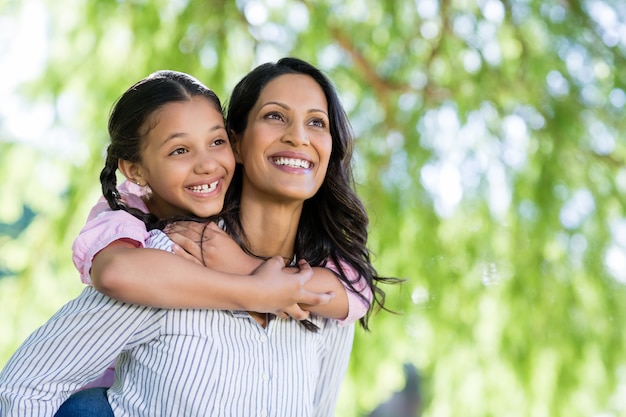 Happy mother giving piggyback ride to her daughter