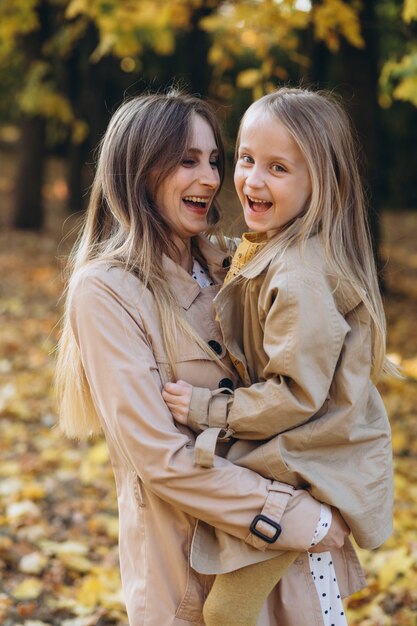 Happy mother and her beautiful daughter have fun and walk in the autumn park.