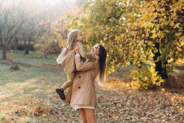 Happy mother and her beautiful daughter have fun and walk in the autumn park.