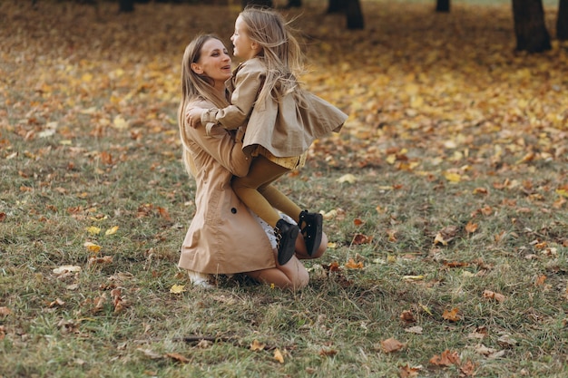 Happy mother and her beautiful daughter have fun and walk in the autumn park.