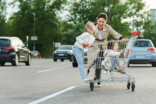 Happy mother and her daughters are having fun with a shopping cart