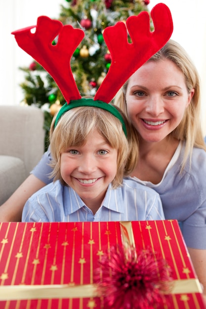Счастливая мать и ее сын распаковывают рождественский подарок
