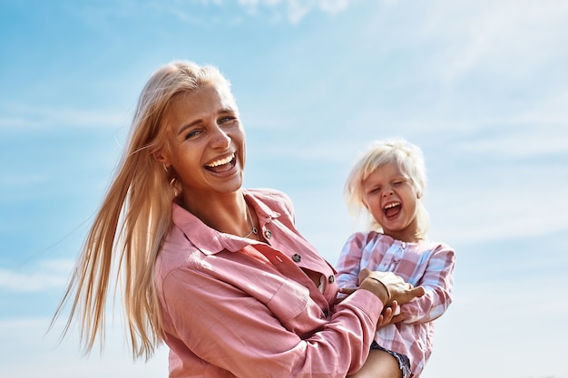 Счастливая мать держит ребенка, улыбаясь на пшеничном поле в солнечном свете