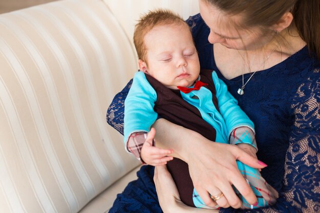 Happy mother holding her baby and playing with him indoors