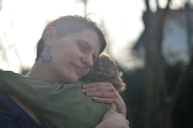 Foto una madre felice che tiene in braccio un bambino con amore in un giardino all'aperto in estate