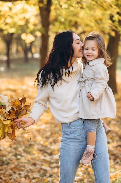 Happy mother holding little daughter in her arms in autumn park