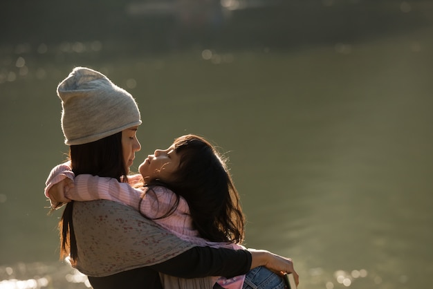 Happy mother hugging with her child in nature on sunny day