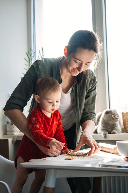 Happy mother and little baby toddler girl making christmas cookies in home kitchen mother and little