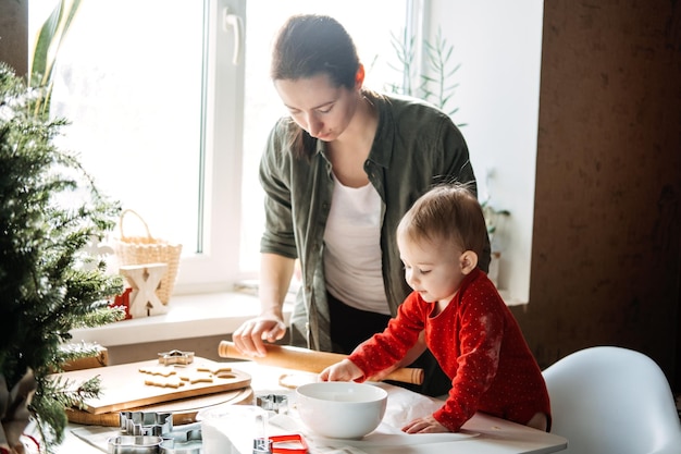 Madre felice e piccola bambina che preparano i biscotti di natale nella cucina di casa madre e piccola