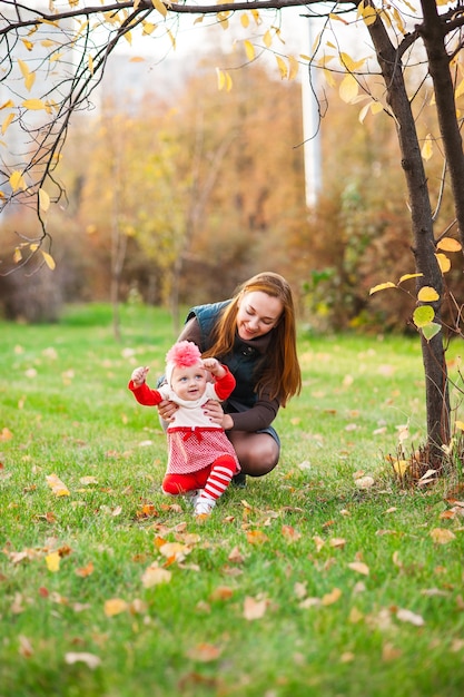 Happy mother and little daughter playing in the autumn park