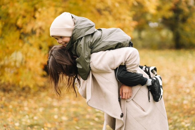 幸せな母と小さな息子秋の森で自然の中で歩いている子供