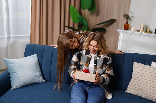 La madre felice guarda con sorpresa il regalo della figlia adulta