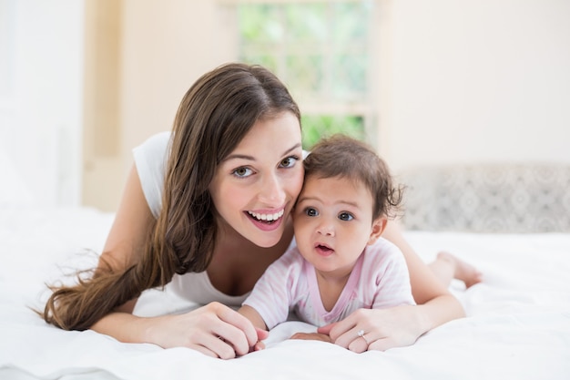 Happy mother lying with baby at home 