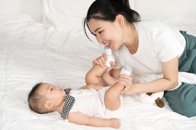 Happy mother playing with baby on a bed at home