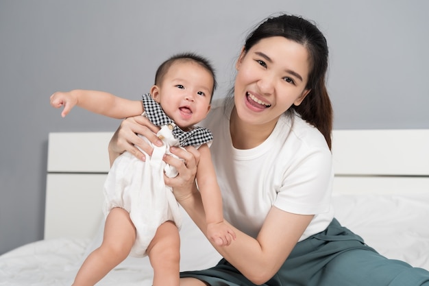 Happy mother playing with baby on a bed at home