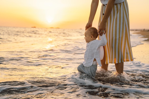 Happy mother's day Beautiful mother and baby play on the beach Mum and her Child together enjoying sunset Loving single mother hugs cute little son