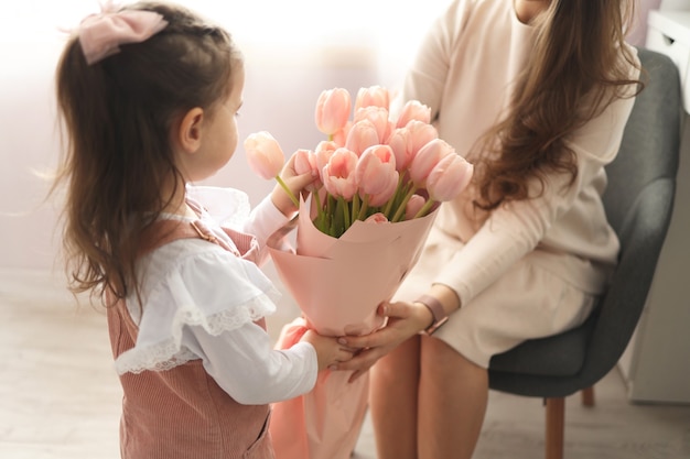 写真 母の日おめでとう！子娘はお母さんを祝福し、ピンクの花にチューリップを贈ります。