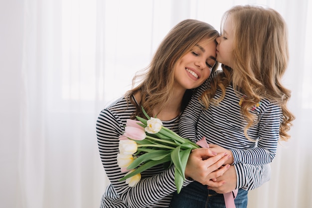 Happy mother's day. Child daughter congratulates moms and gives her flowers tulips.