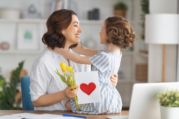 Happy mother's day Child daughter congratulating mom and giving her flowers