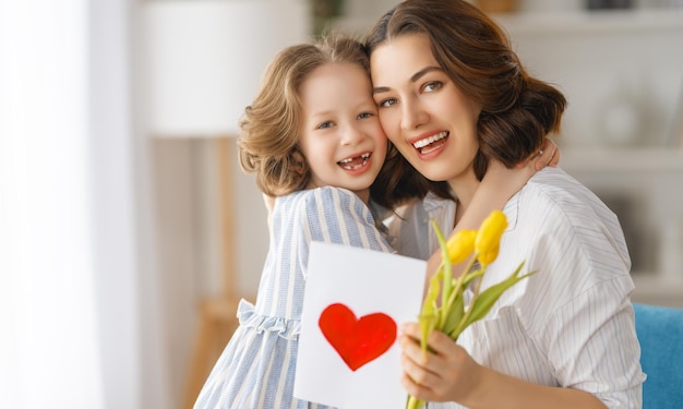 Happy mother's day Child daughter congratulating mom and giving her flowers