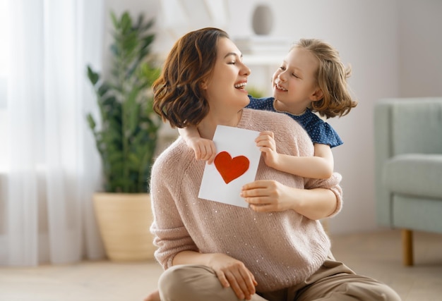 Buona festa della mamma la figlia del bambino si congratula con la mamma e le dà la cartolina