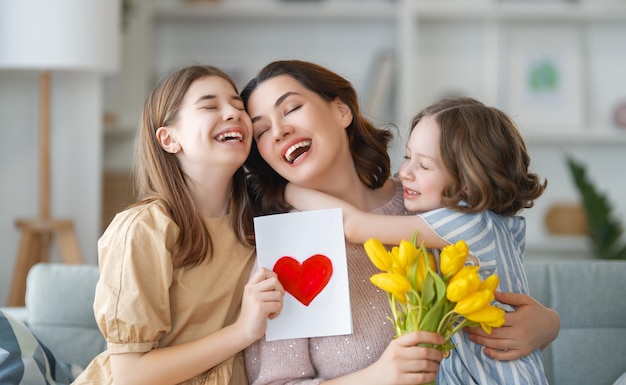 Buona festa della mamma le figlie dei bambini si congratulano con la mamma e le regalano fiori