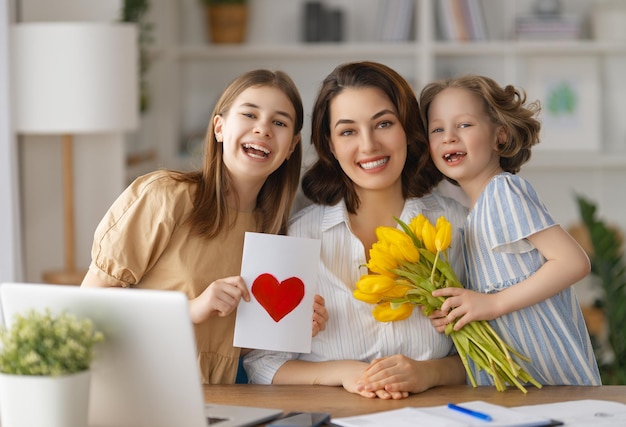 Happy mother's day Children daughters are congratulating mom and giving her flowers