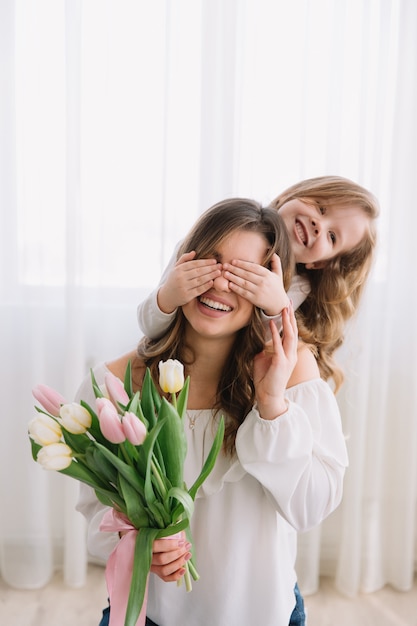 Фото Концепция день счастливой матери. детская дочка поздравляет маму и дарит ей цветы тюльпанов