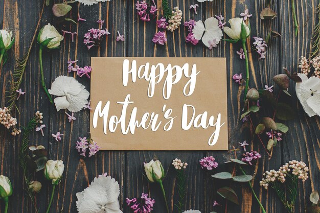 Happy mother's day Happy mother's day text on card and lilac eucalyptus hydrangea rose flowers on rustic dark wood flat lay Stylish floral greeting card Handwritten lettering Mothers day