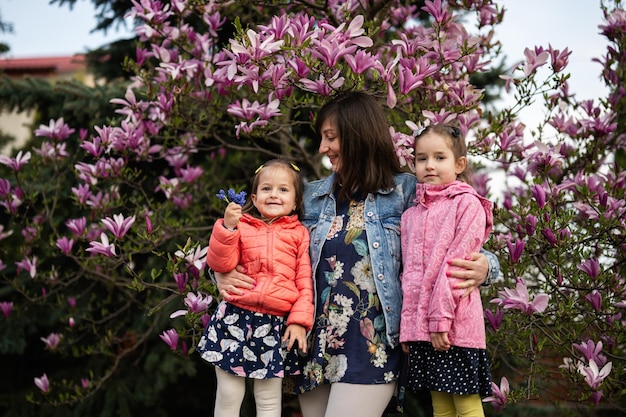 Happy mother's day moeder met twee dochters genieten van een mooie lentedag in de buurt van magnolia bloeiende boom