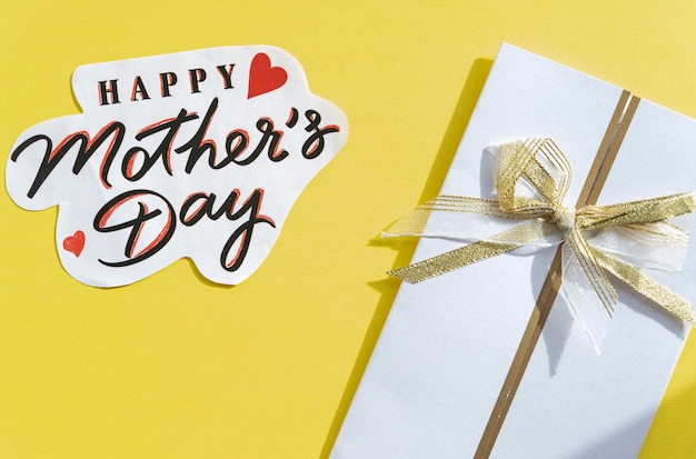 Happy mother's day tekst en witte envelop op gele achtergrond bovenaanzicht Stijlvolle wenskaart concept plat leggen moeders dag lente imagehandgeschreven letters