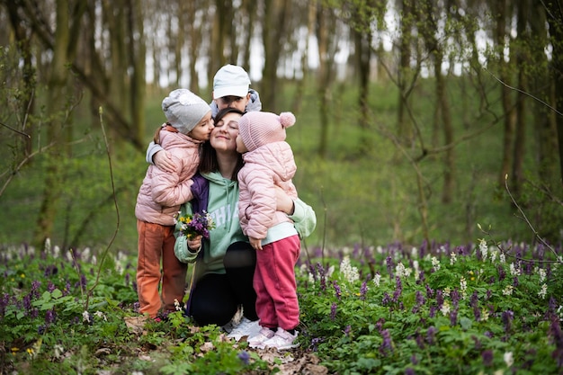 Buona festa della mamma ti amiamo mamma madre con un mazzo di fiori e tre bambini nella foresta in fiore primaverile