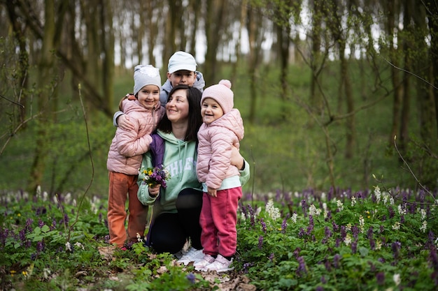 Happy Mother's Day We love you mom Mother with a bouquet of flowers and three kids in spring blooming forest