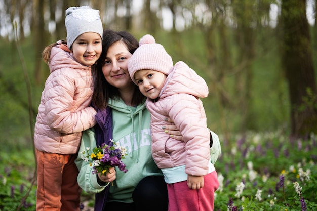 Buona festa della mamma ti amiamo mamma madre con un mazzo di fiori e due figlie nella foresta in fiore primaverile