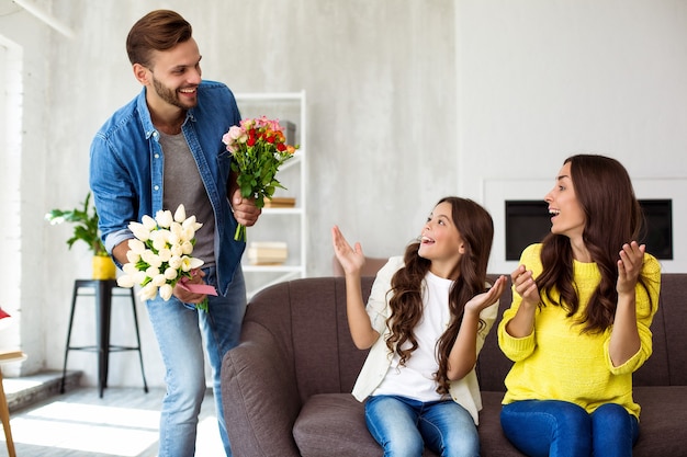 幸せな母または女性の日。女性の日を祝う興奮した素敵な家族。夫は彼の妻と小さなかわいい娘のためにサプライズを準備しました