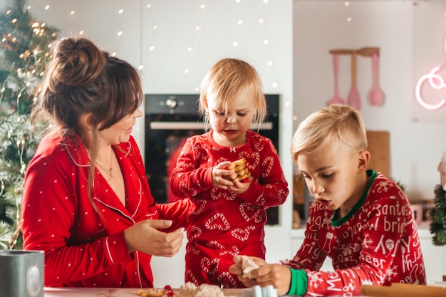 Happy mother, son and daughter bake cookies for christmas in the white kitchen